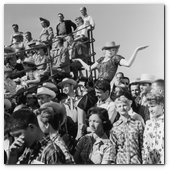 :: Pulse para Ampliar :: 1956:  EXCLUSIVE American actor Marilyn Monroe (1926 - 1962) reacts while American actor Don Murray carries her on his shoulder on the set of director Joshua Logan's film, 'Bus Stop'. They are surrounded by a crowd in bleachers. Monroe is wearing a cowboy hat, a blouse and a slit skirt.  (Photo by Hulton Archive/Getty Images)