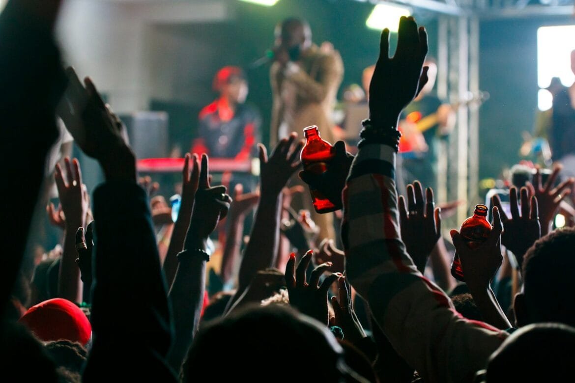 a crowd of people at a concert with their hands in the air