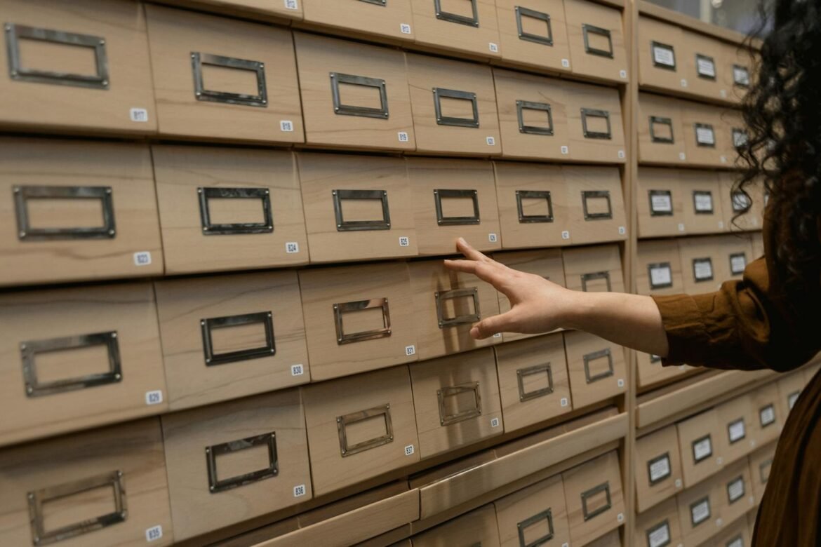 A person organizing wooden drawers in an archive room with a focus on storage.