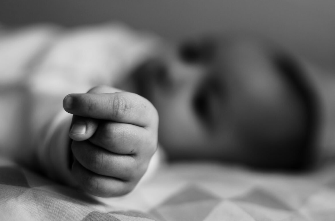 Photo by Flávia Gava grayscale photo of baby lying on bed
