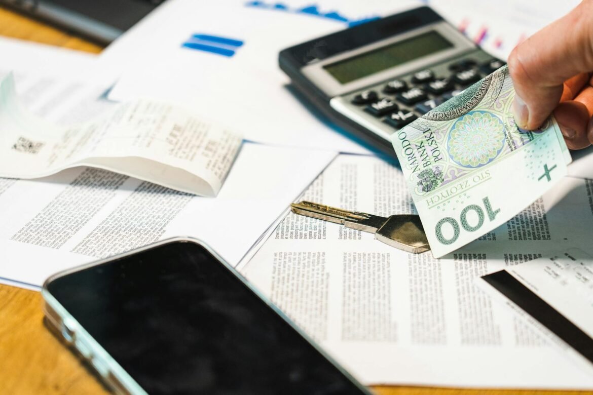 Close-up of financial documents, calculator, and Polish Zloty currency on a desk.