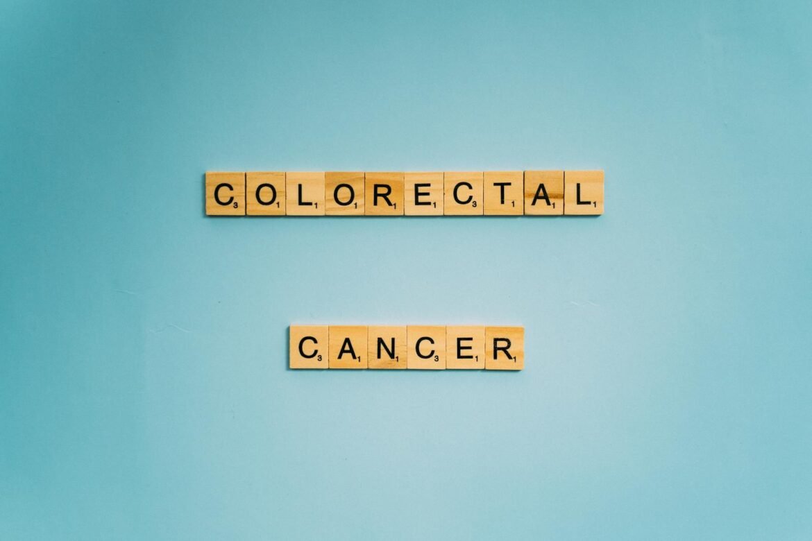 Scrabble tiles spell 'Colorectal Cancer' on a light blue background for cancer awareness.