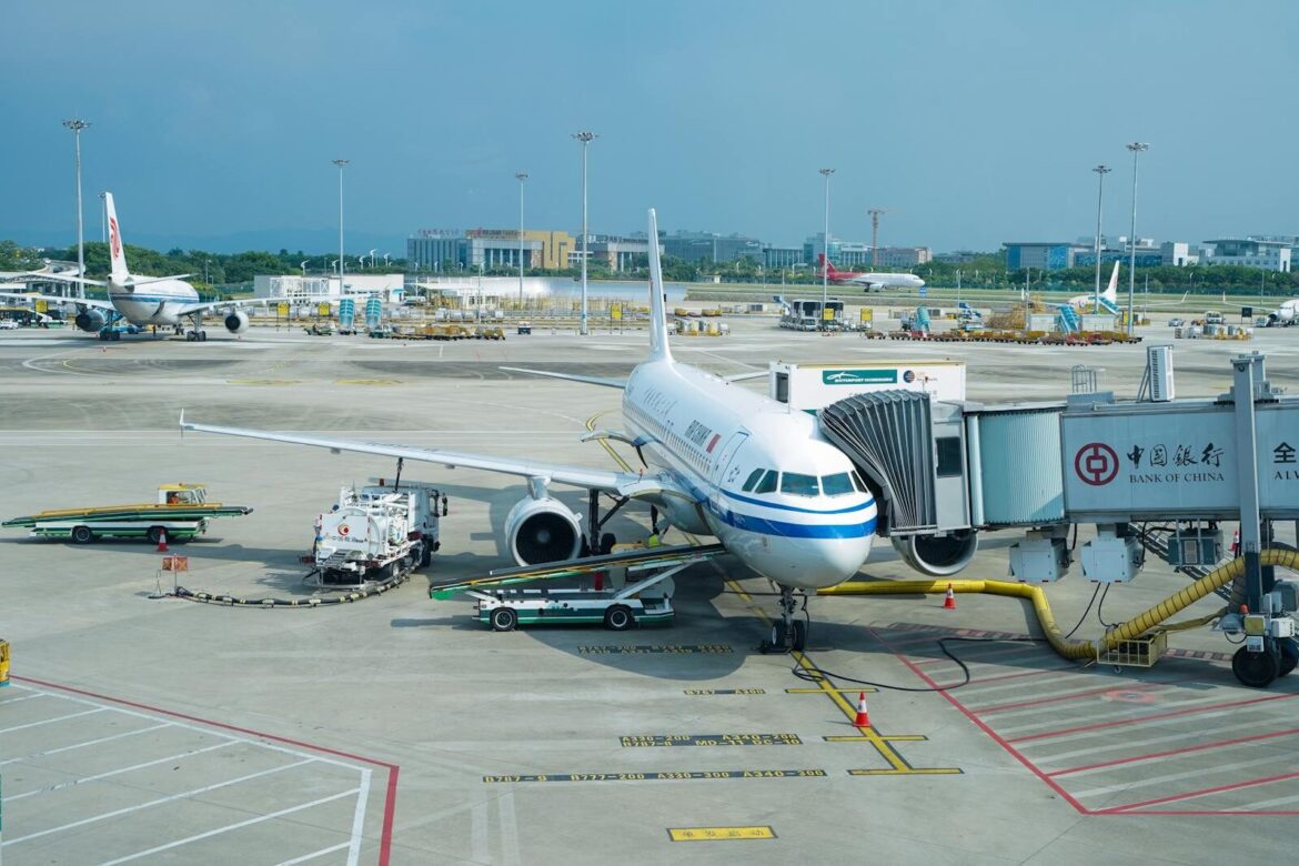 Airplane parked at a terminal gate with boarding bridge in a bustling airport.