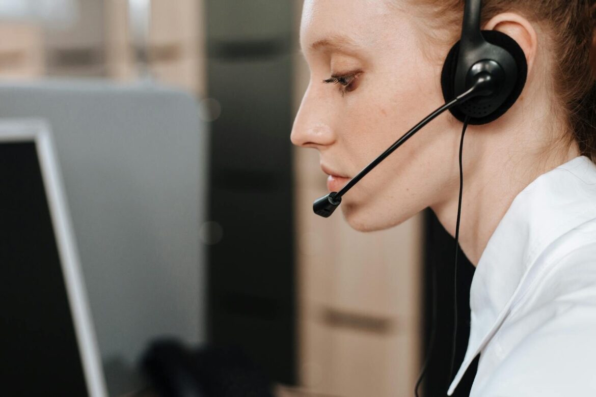 Close-up of a female call center agent using a headset while working at her desk.