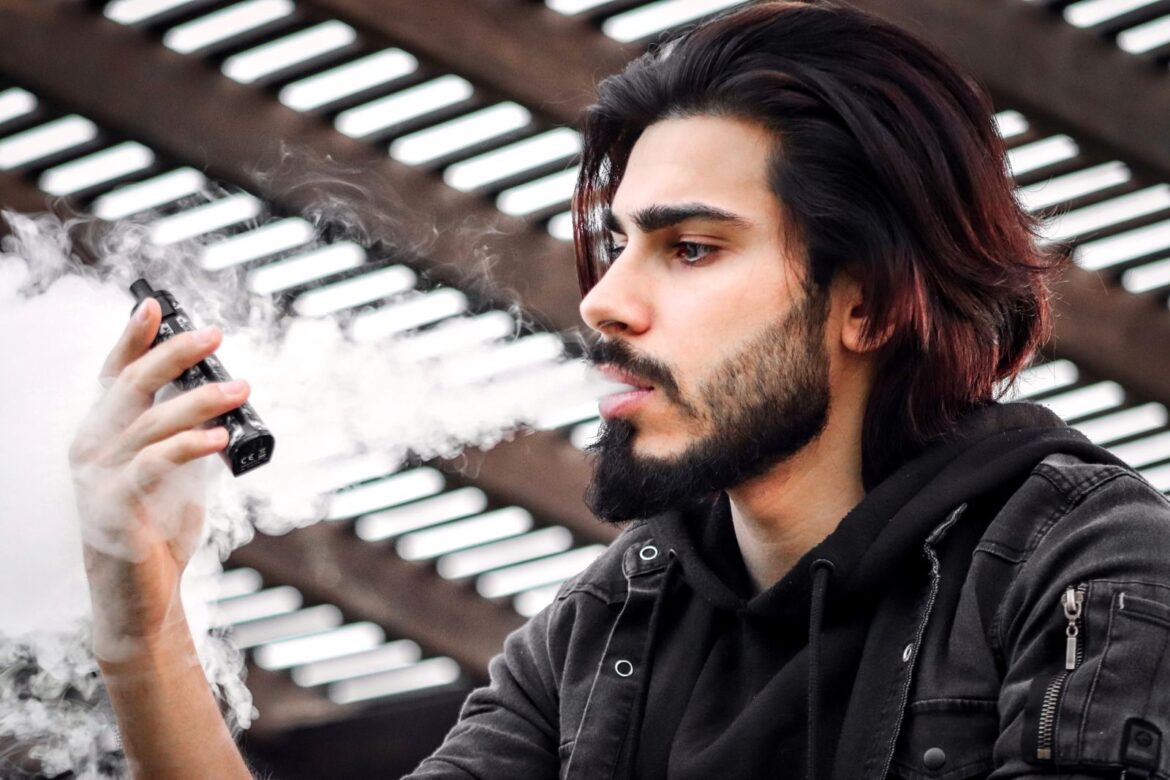 Portrait of a young man vaping outdoors in Dubai, showcasing modern lifestyle and fashion.