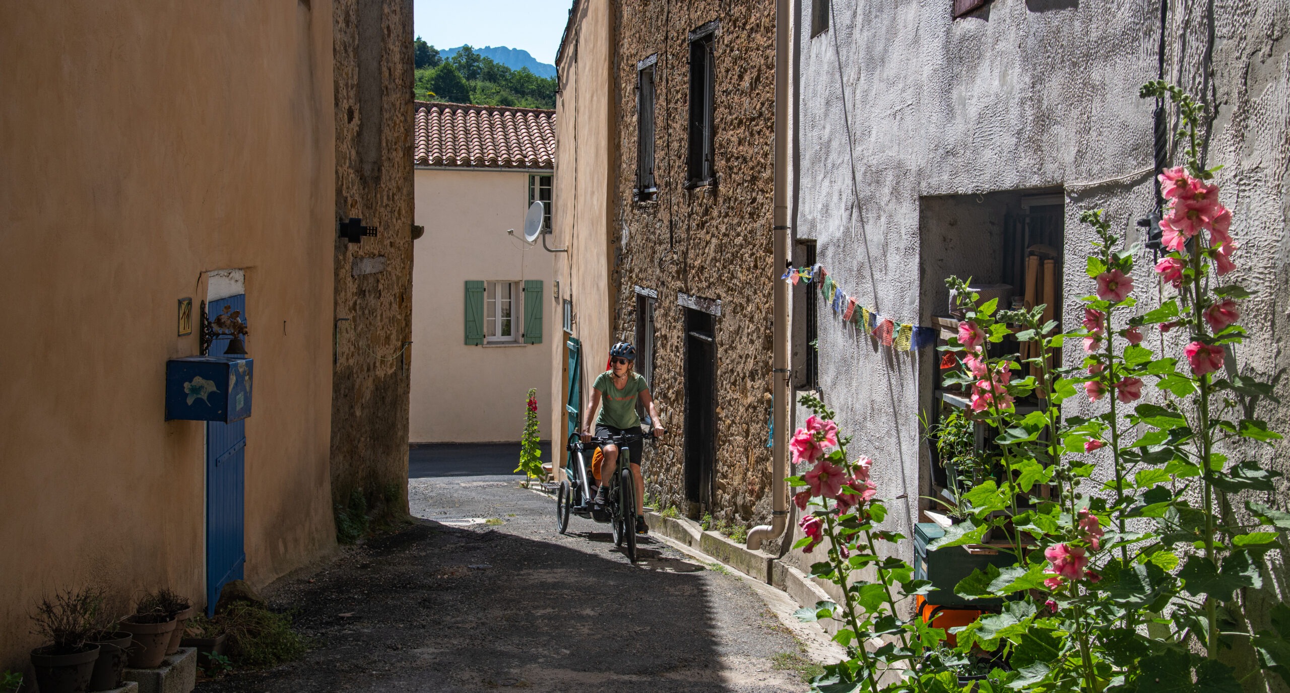 bugarach-2023-06-v81-femme-velo-remorque-ruelle-ombre-village-by-gaillard-munsch-ag-pyr